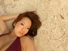 Asiatique aux mamelles volumineuses se trouve nue sur la plage