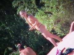 Two brunettes and one blonde on a nudist beach tanning and bending