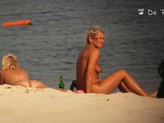 Two blondies are having a good time on the beach with naked boobs