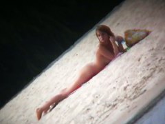 Hot body babe lying down on the beach surprised by a spy cam
