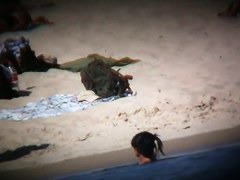 Topless ladies surrounded by dressed men at the beach