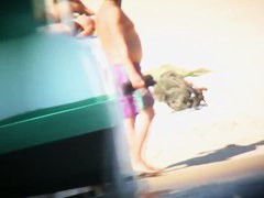 Topless ladies surrounded by dressed men at the beach