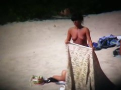 Topless ladies surrounded by dressed men at the beach