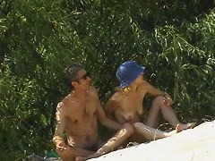 Couple taking sunbaths and walking nakes on the beach