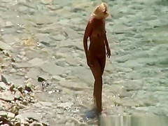 Blonde nudist woman enters the water