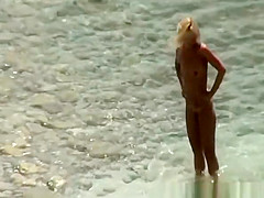 Blonde nudist woman enters the water