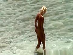 Blonde nudist woman enters the water