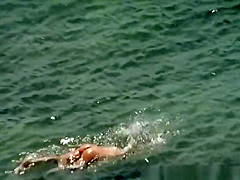 Blonde nudist woman enters the water