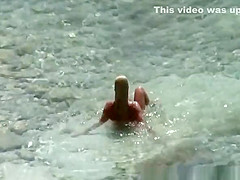 Blonde nudist woman enters the water