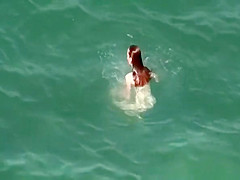 Nudist redhead swimming in the water