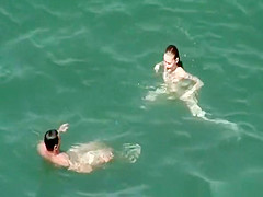 Nudist redhead swimming in the water