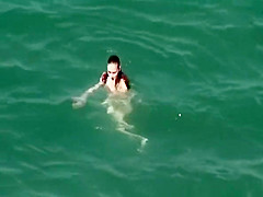Nudist redhead swimming in the water