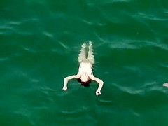 Nudist redhead swimming in the water