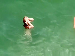 Nudist redhead swimming in the water