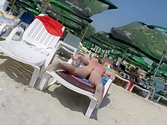 Oiled up milf sunbathes in topless