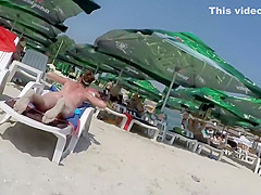 Oiled up milf sunbathes in topless