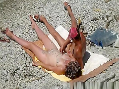 Man puts small rocks on his nude wife's body