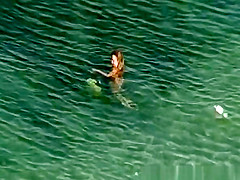 Nude woman swimming and drinking