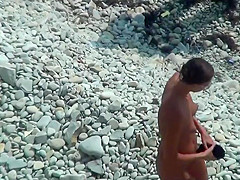 Girl with plug in the ass poses for a guy at a public beach