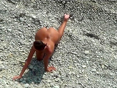 Girl with plug in the ass poses for a guy at a public beach