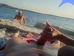 On a nude beach the wife stokes my cock while a voyuer watches