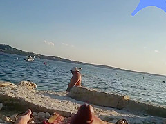 On a nude beach the wife stokes my cock while a voyuer watches