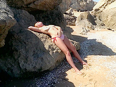 Marta is resting on a wild beach, caressing themselves