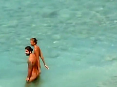 Couple strips and blows on the beach