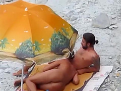 Couple strips and blows on the beach