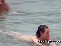 Naked ladies are enjoying on the beach and not being shy while people are watching them