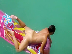 Hot nudist woman sunbathing in inflated air mattress