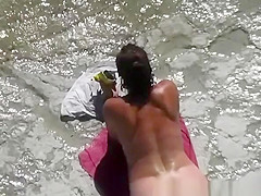 Nudist woman in her red towel sunbathing