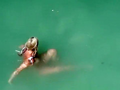 Blonde nudist chick swimming in the water