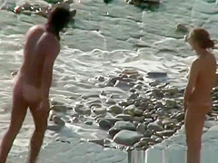Nudist woman with sunglasses at the rocky beach