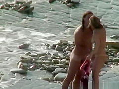 Nudist woman with sunglasses at the rocky beach