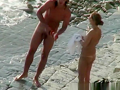 Nudist woman with sunglasses at the rocky beach