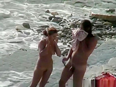 Nudist woman with sunglasses at the rocky beach