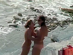 Nudist woman with sunglasses at the rocky beach