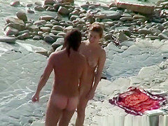 Nudist woman with sunglasses at the rocky beach