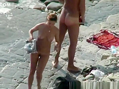 Nudist woman with sunglasses at the rocky beach