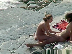 Nudist woman with sunglasses at the rocky beach