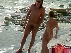Nudist woman with sunglasses at the rocky beach