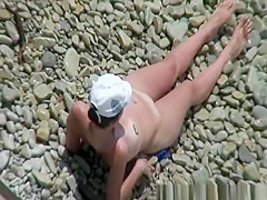 Nude woman in rocky beach sunbathing