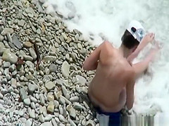 Nude woman in rocky beach sunbathing