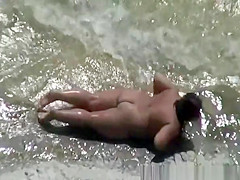 Chubby nudist woman sunbathing and swimming