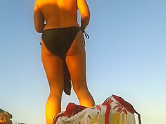 Blonde nudist in sunglasses at beach