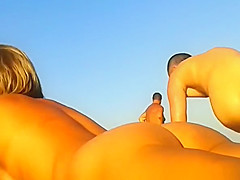 Blonde nudist in sunglasses at beach