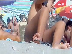 Tattooed nude woman sunbathing at nudist beach