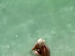 Busty blonde nudist swimming in the water