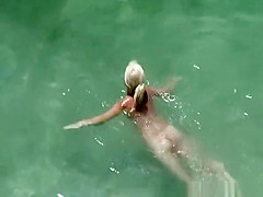 Busty blonde nudist swimming in the water